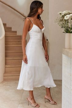 a woman in a white dress standing next to stairs