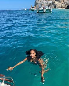 a woman swimming in the ocean next to a boat