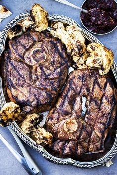 two steaks on a platter with other foods