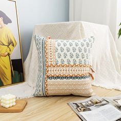 a pillow sitting on top of a wooden floor next to a painting and a magazine