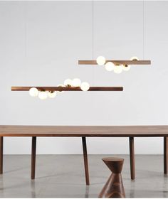 three lights hanging over a wooden table in a room with white walls and flooring