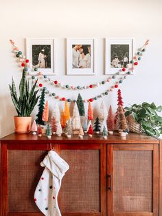 christmas decorations and pictures on a wall above a wooden cabinet