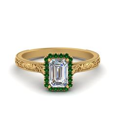 an emerald and diamond engagement ring with filigrees on the sides, set in yellow gold