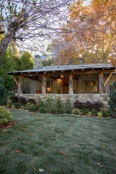 a small cabin style house in the middle of a field with trees and grass around it