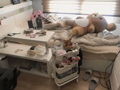 a teddy bear sitting on top of a bed next to a desk with several other items