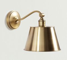 an antique brass wall light with a white back ground and a gold shade on the side