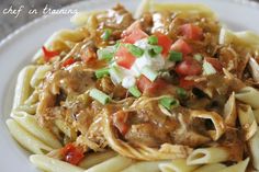 a white plate topped with pasta and meat covered in sauce, cheese and tomato slices