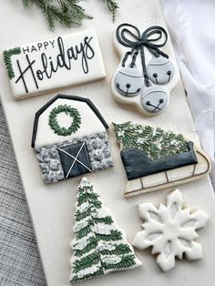 decorated cookies are displayed on a white board with evergreens and snowflakes around them