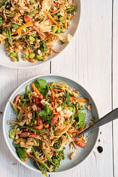 two white bowls filled with salad on top of a wooden table