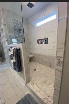 a bathroom with white tile and marble flooring is shown in this image, there are towels hanging on the shower door