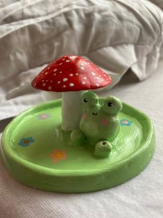 a green plate with a mushroom and frog figurine on it