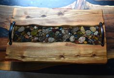 a wooden tray with rocks in it on top of a table next to a wall