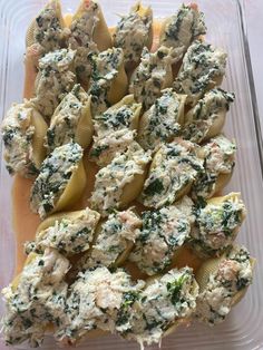 a plastic container filled with stuffed shells covered in spinach and fettuccine