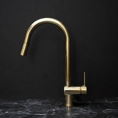 a gold faucet on a marble countertop in a kitchen with black walls