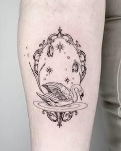 a woman's leg with a black and white swan tattoo on the side of her thigh