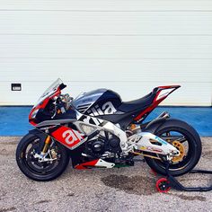 a red and black motorcycle parked in front of a garage