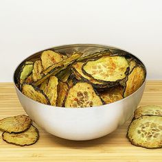 a bowl filled with sliced up zucchini on top of a wooden table