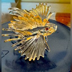 a glass sculpture is sitting on top of a blue plate with gold trimmings