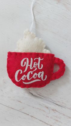 a hot cocoa cup ornament hanging from a string