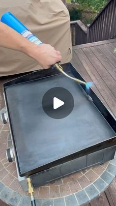 a man is using a hose to clean an outdoor grill