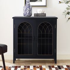 a black cabinet with two glass doors and a vase on top