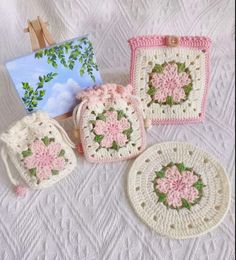 four crocheted purses are sitting on a white tablecloth next to an easel