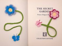 an open book with crocheted flowers and butterflies on the cover, in front of a white background