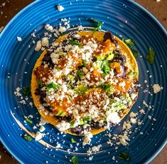 a blue plate topped with an omelet covered in cheese and toppings on top of it