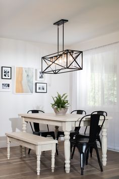 a dining room table with chairs and a bench in front of the chandelier