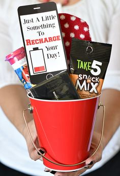 a woman holding a red bucket filled with snacks and other items, including a cell phone