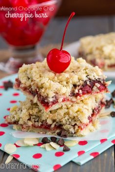 two pieces of cherry pie bars stacked on top of each other with a cherry in the background