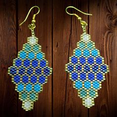 blue and green beaded earrings hanging from wooden background with wood planks in the background