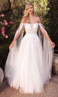 a woman in a white wedding dress posing for the camera with her hands on her hips