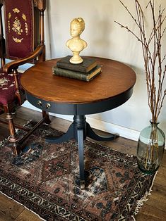 a table with two books on top of it next to a chair and vases