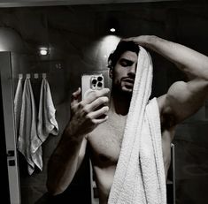 a shirtless man taking a selfie in front of a mirror with his phone