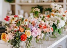 a row of vases filled with colorful flowers on top of a white countertop