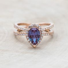 an engagement ring with a pear shaped blue stone surrounded by diamonds