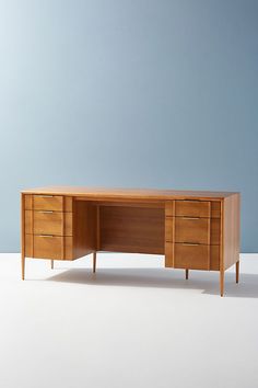 a wooden desk with two drawers on one side and a blue wall in the background