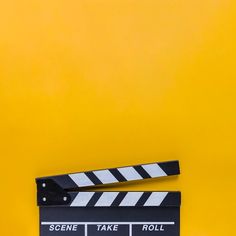 a movie clapper sitting on top of a yellow background