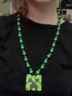 a woman wearing a black shirt and green beaded necklace with an elephant pendant on it