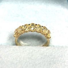 a yellow gold ring with five stones in it on a white cloth covered tablecloth