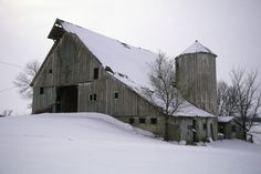 an old barn with snow on the roof