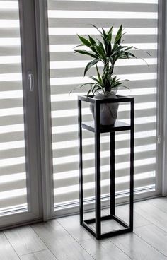 a potted plant sitting on top of a metal stand in front of a window