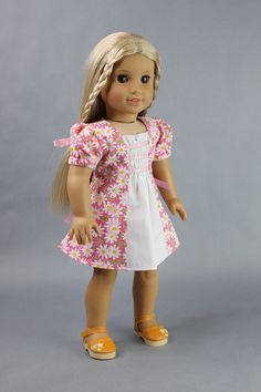 a doll with blonde hair wearing a pink and white dress, yellow shoes and braid