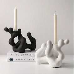 two black and white candles sitting on top of a book next to each other with one candle in the shape of a man