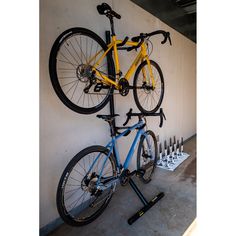 a bicycle mounted to the side of a wall with two bikes on it's back