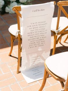 two wooden chairs sitting next to each other with a sign on the back of them