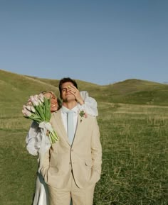 a man and woman are standing in the grass with flowers on their lapel covers