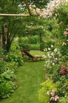 a garden with lots of flowers and plants in the grass next to a wooden bench