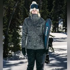 a woman standing in the snow holding a snowboard